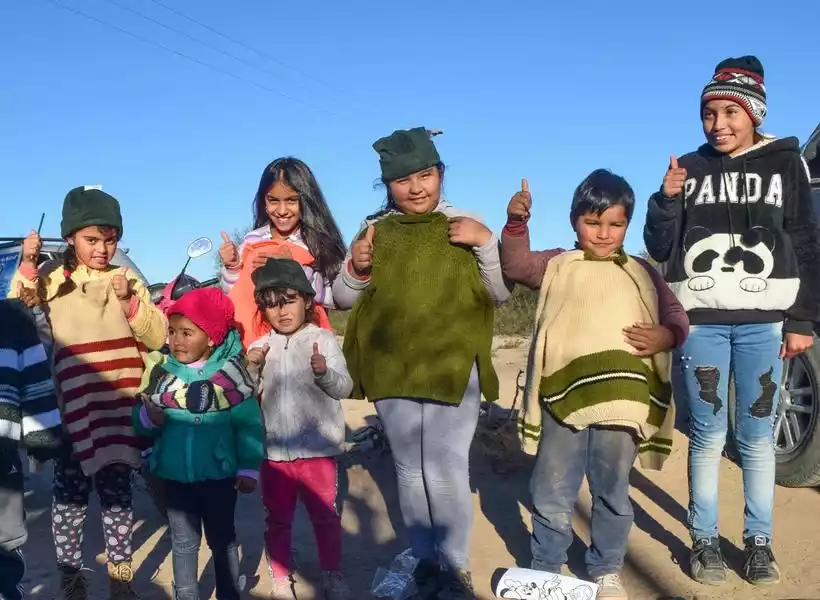 Niños con ropas donadas nuevas levantando el pulgar hacia la cámara