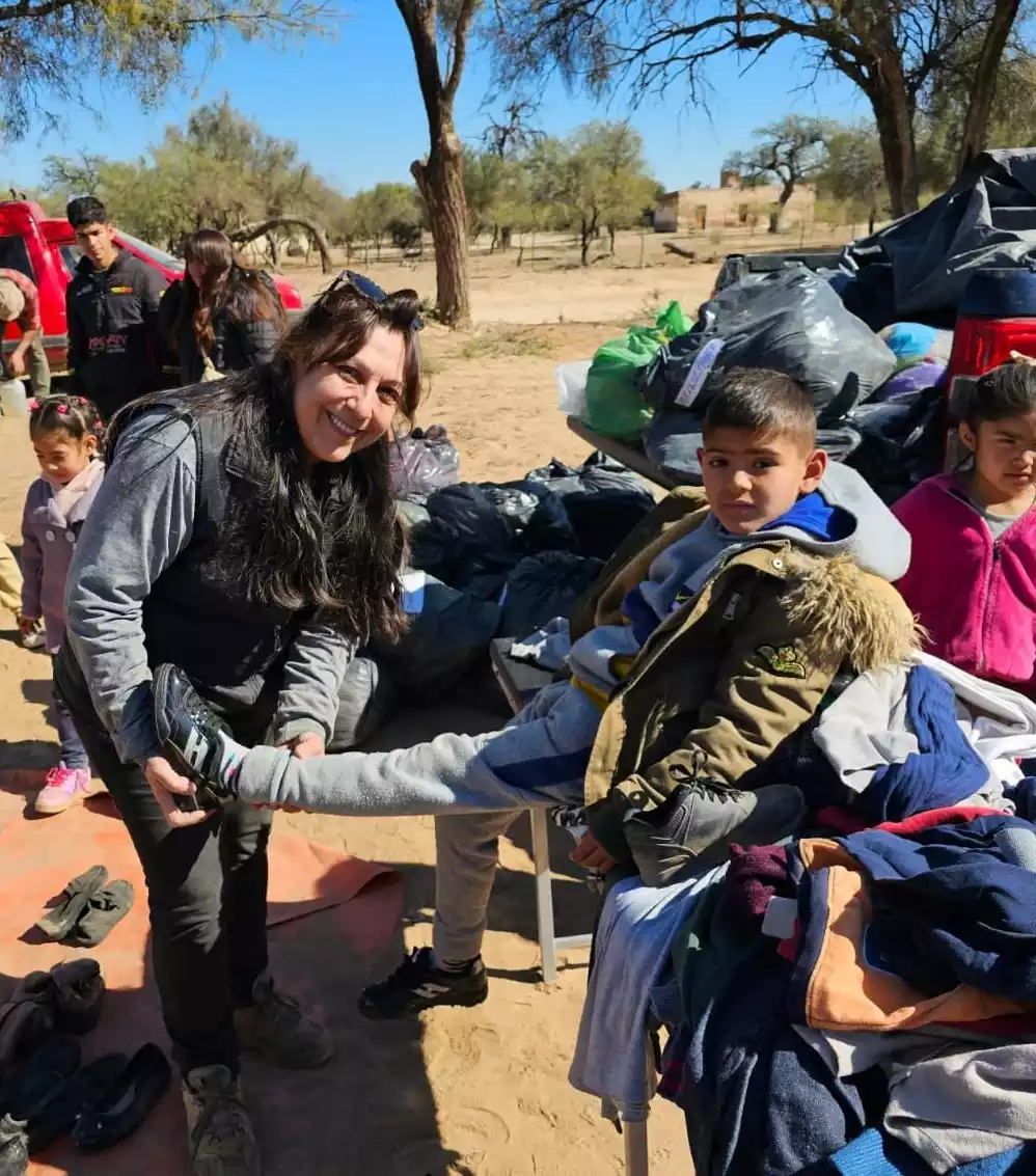 Voluntaria probando un calzado nuevo a niño.