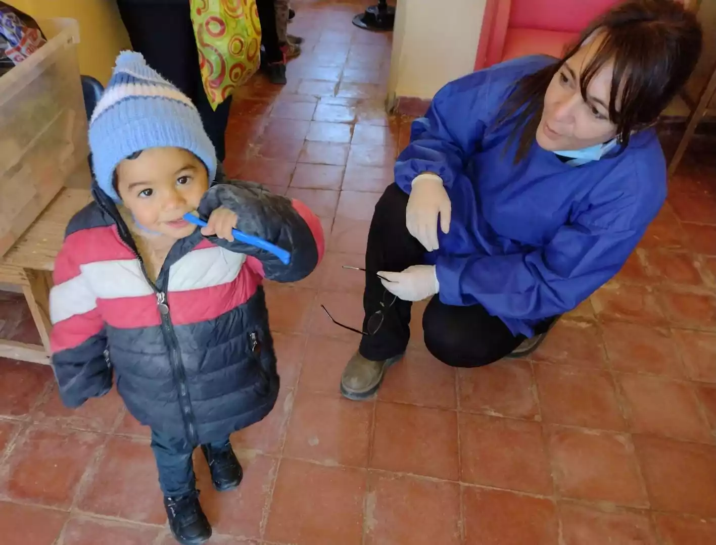 Odontóloga mirando a niño con cepillo de dientes.